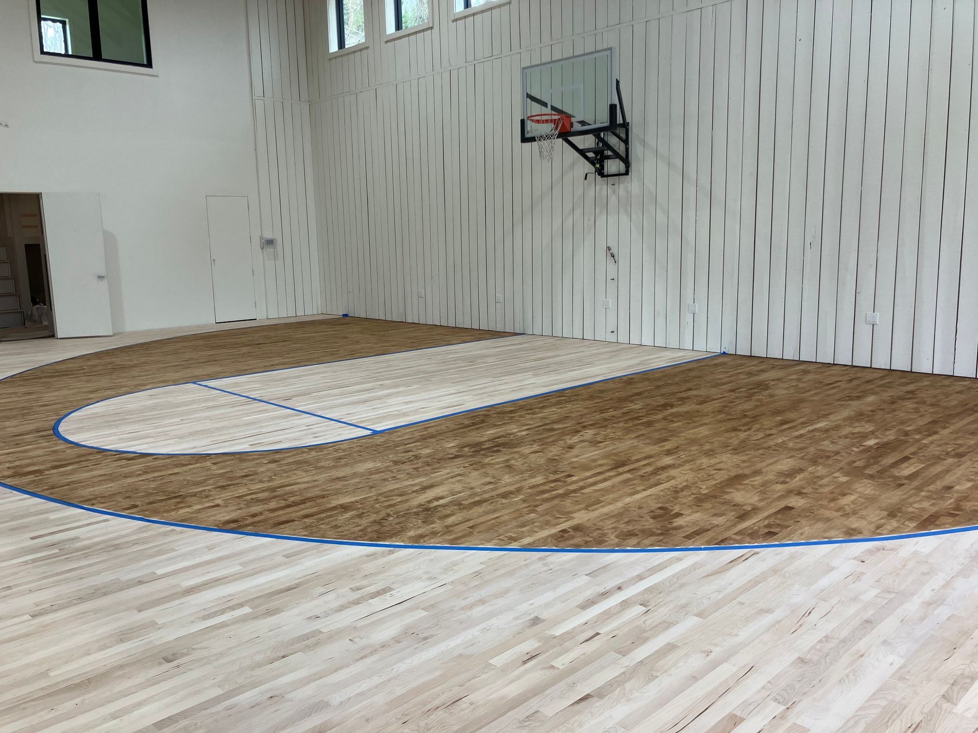 Empty indoor basketball court with a wooden floor and wall-mounted hoop