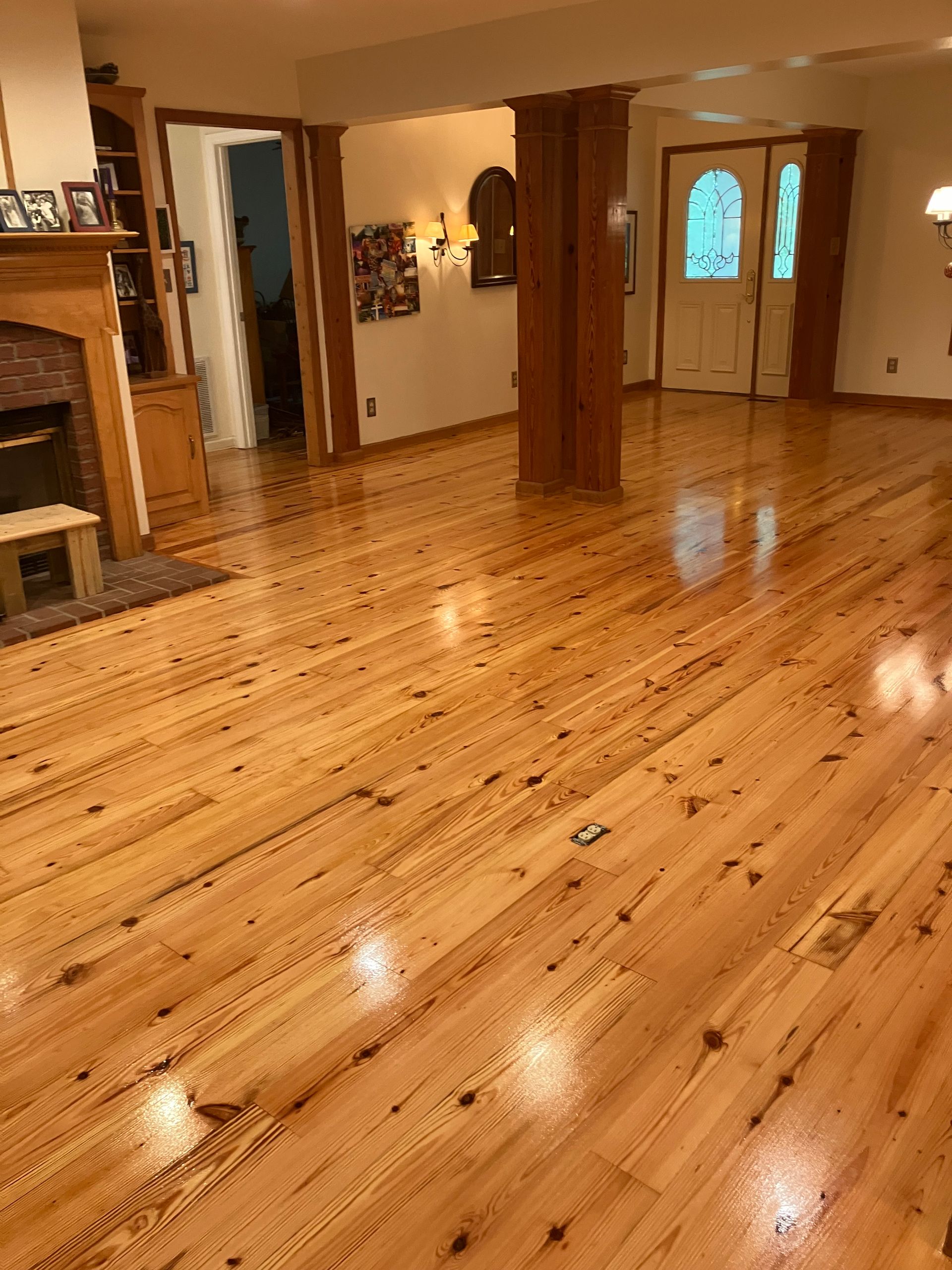 Polished wooden floor in a spacious home interior with a staircase, wooden pillars, and glass double doors