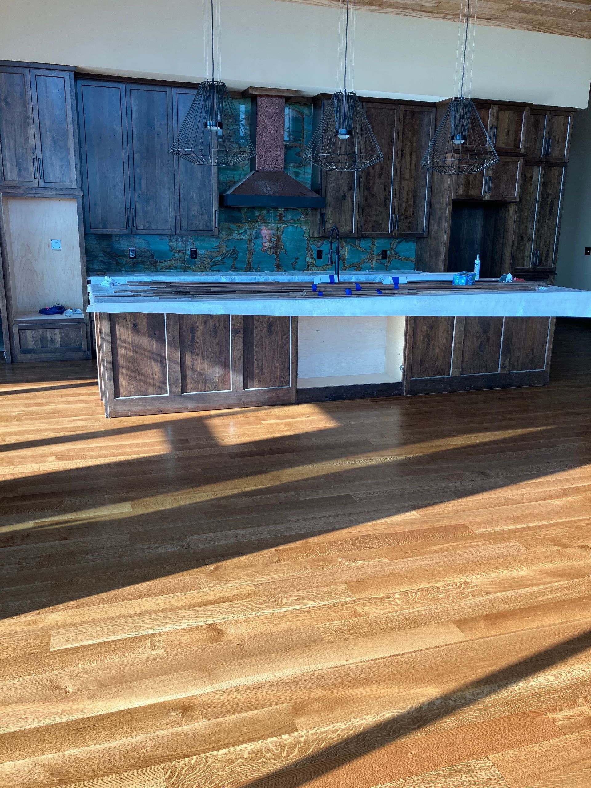 Rustic kitchen with wooden cabinets, turquoise backsplash, and bright sunlight on the hardwood floor
