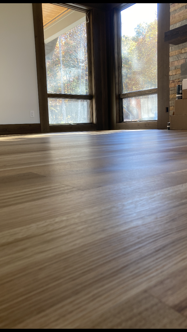 Empty room with wood floor and large windows letting in sunlight