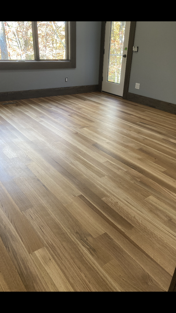 Empty room with light wood floors, gray walls, a window, and a glass door.