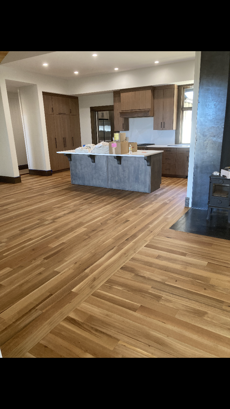 Open-plan kitchen with gray island, wood floors, and recessed ceiling lights