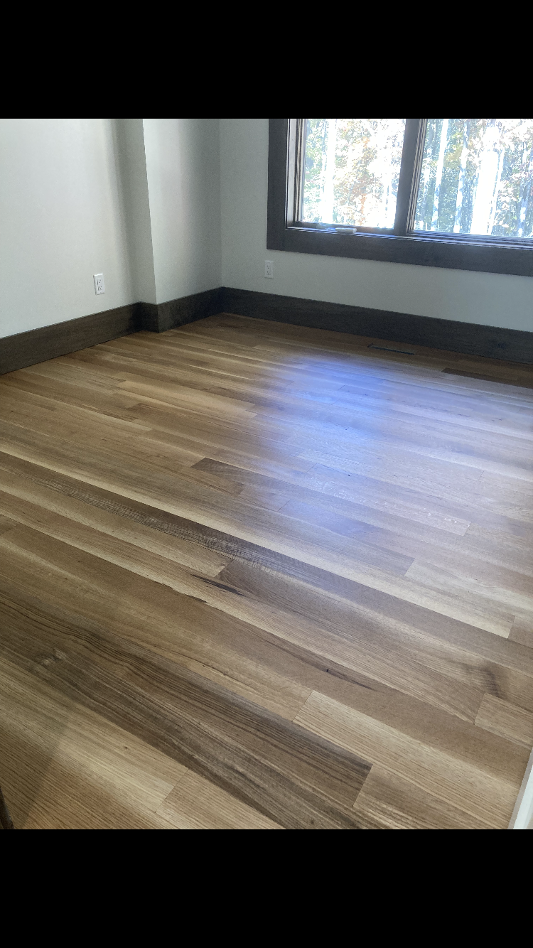 Empty room with wood-look flooring, white walls, and a window letting in daylight