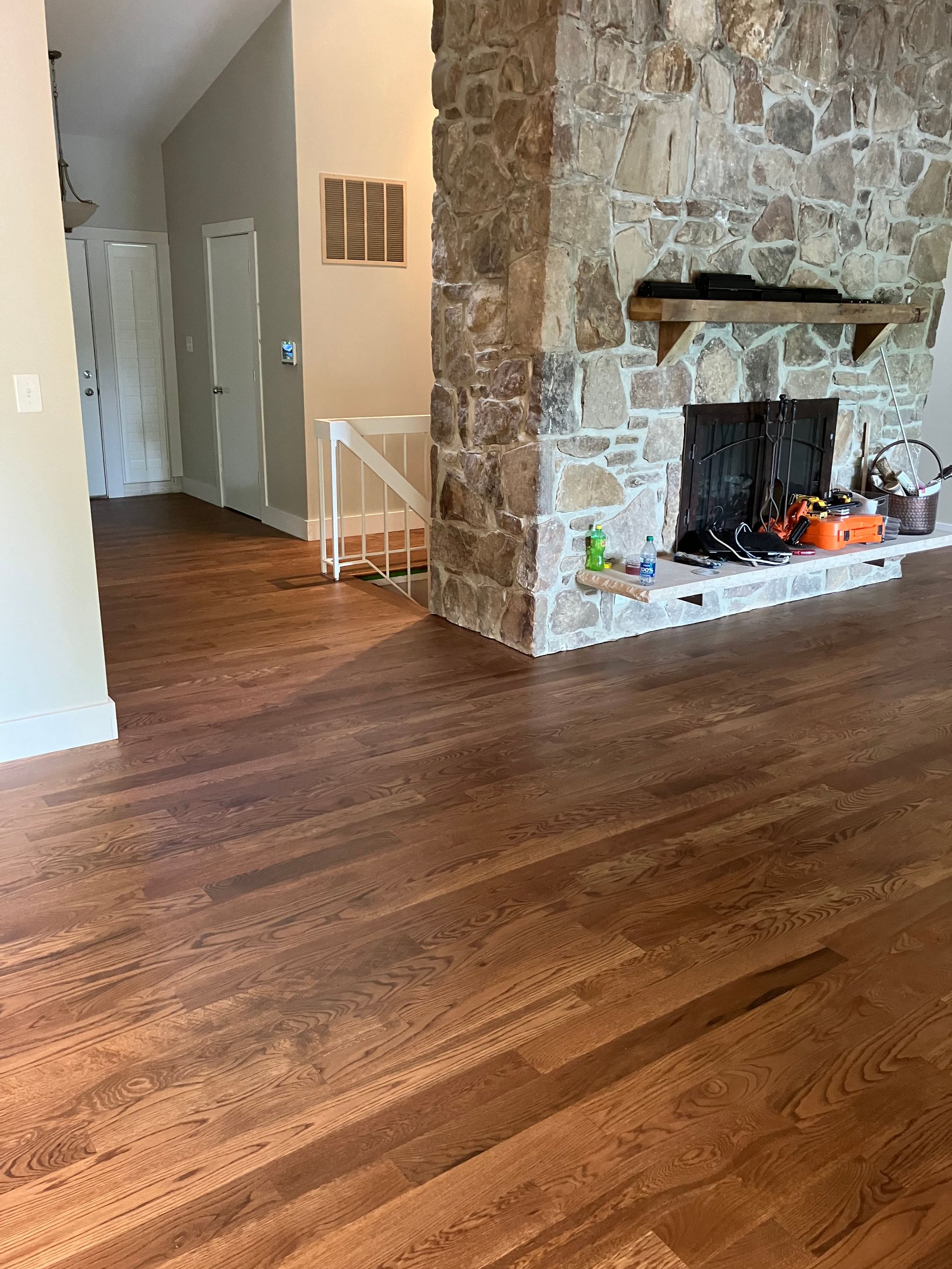 Empty living room with wood floors and a stone fireplace.