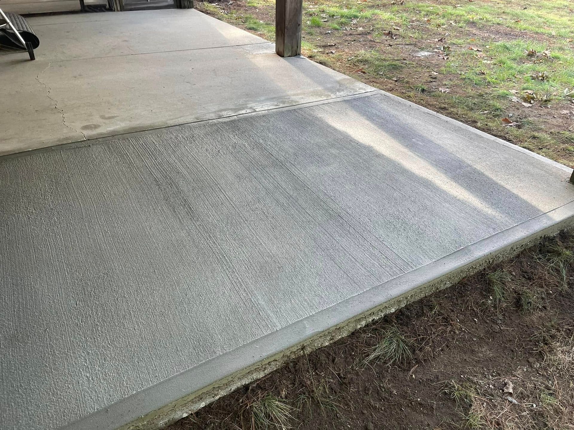 Concrete sidewalk ramp beside a grassy slope under a covered walkway