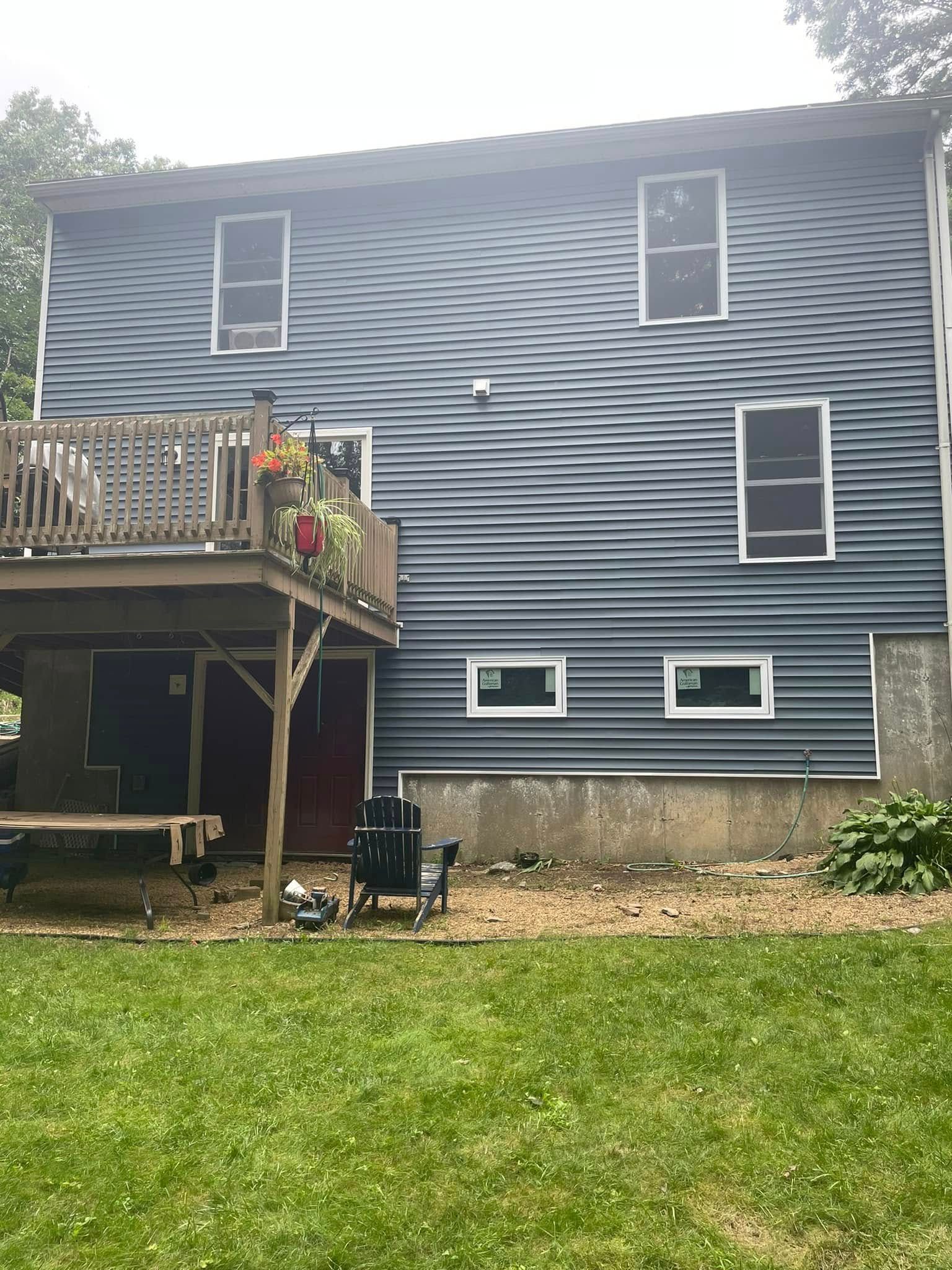 Back of a blue house with deck, white-trim windows, and grassy yard