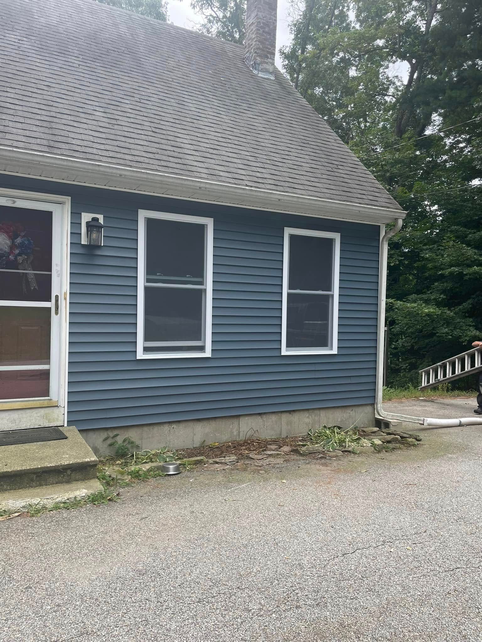 Blue house exterior with white-trimmed windows and a gravel driveway