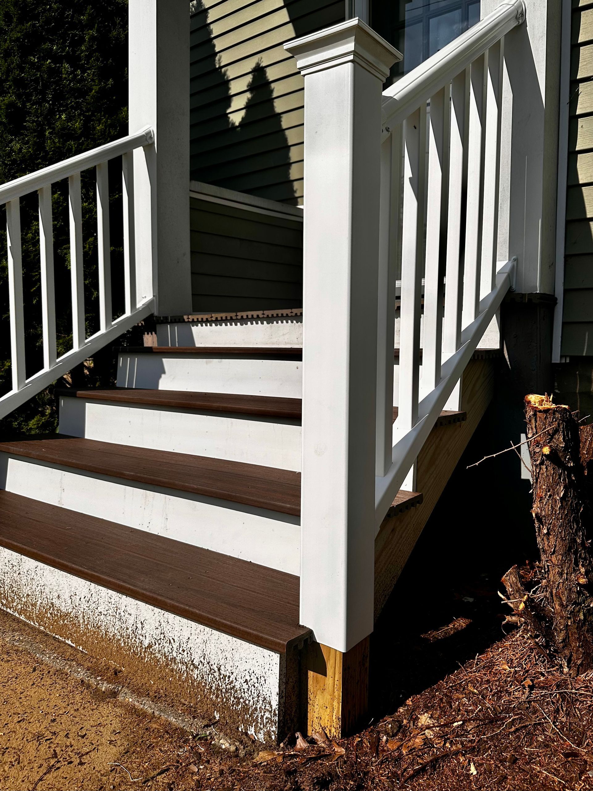 Front steps with white railings and brown treads leading to a house entrance