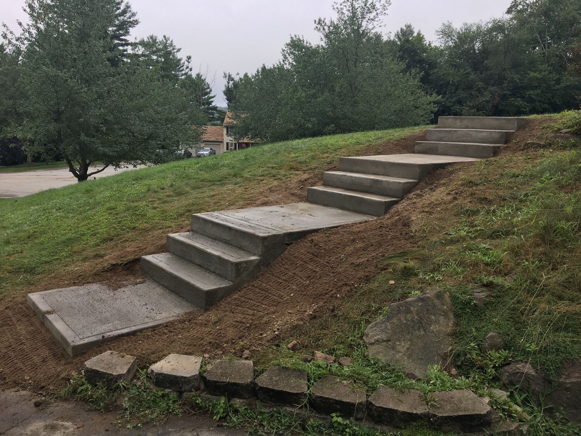 Concrete stairs built into a grassy hillside with trees in the background.