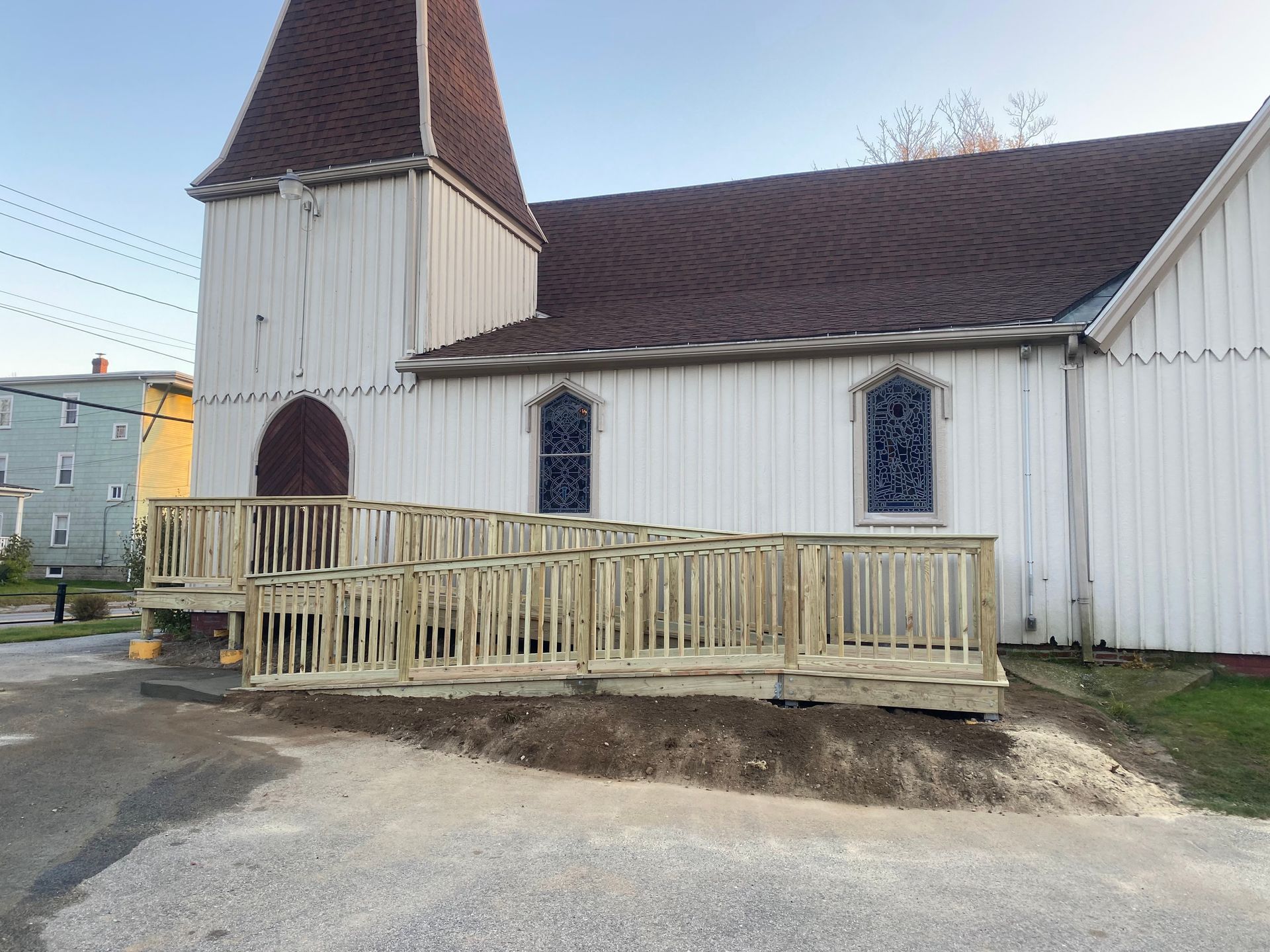 White church with wooden steeple and small ramped porch on a street corner