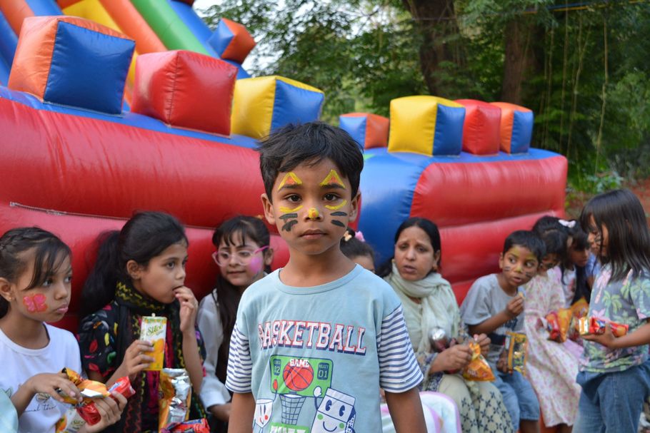 Children at an outdoor fair with a colorful inflatable bounce house in the background