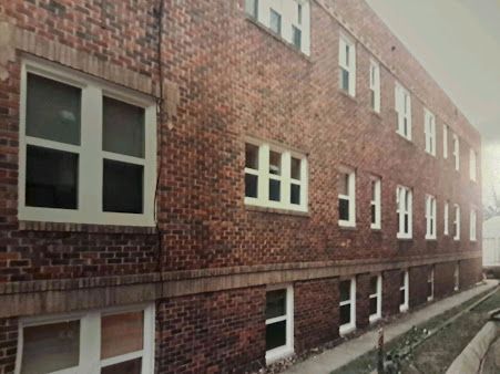 Red brick apartment building with white-trimmed windows along a narrow walkway