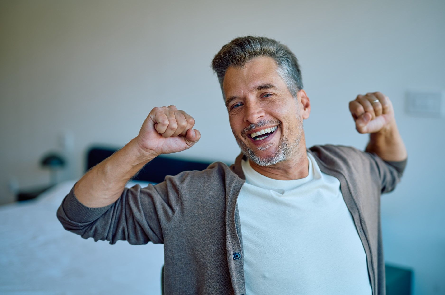 Smiling person stretching with raised fists in a bright room