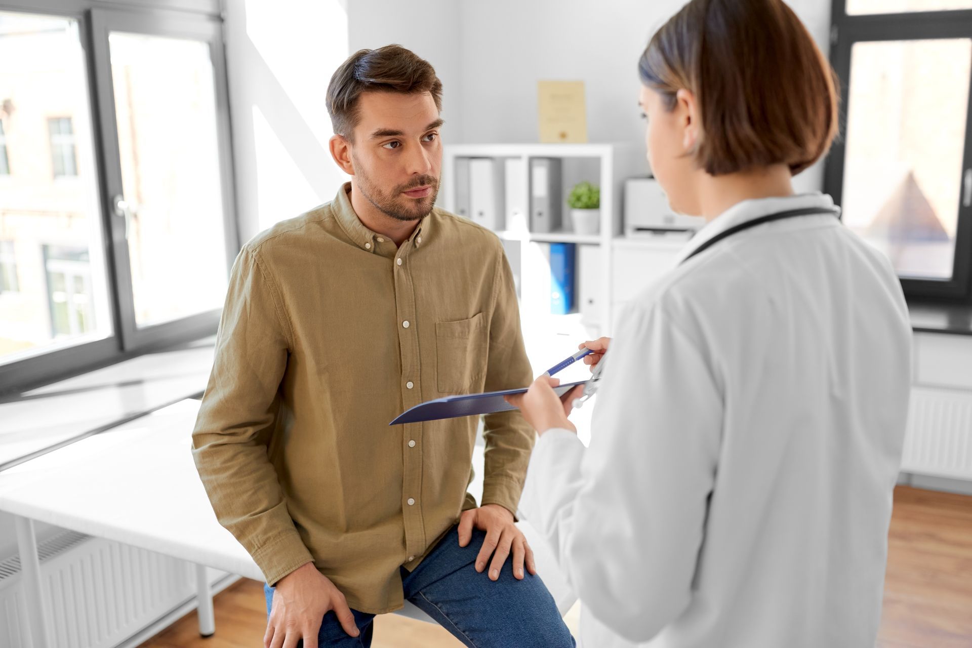 Doctor talking with a seated patient in a bright clinic office
