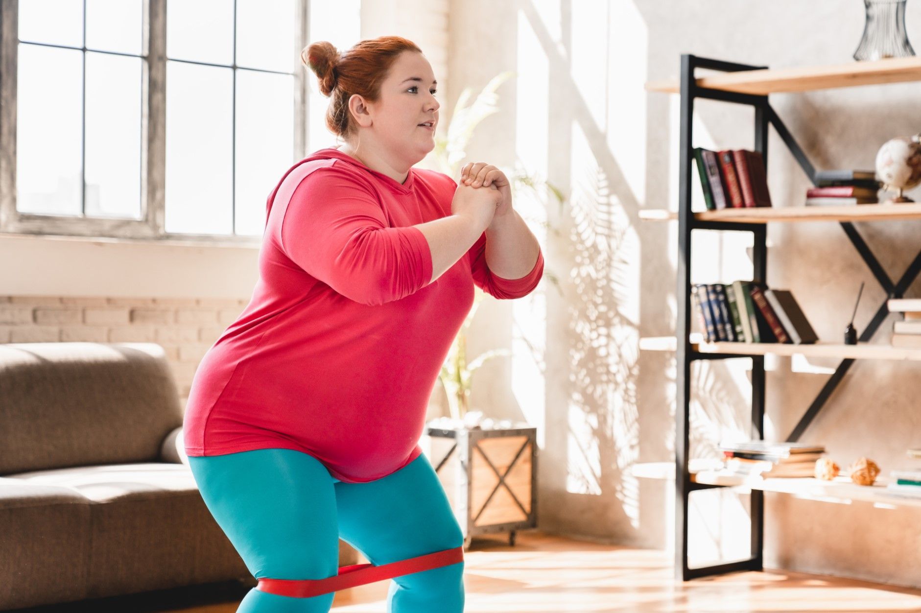 Woman doing a resistance-band squat in a bright living room