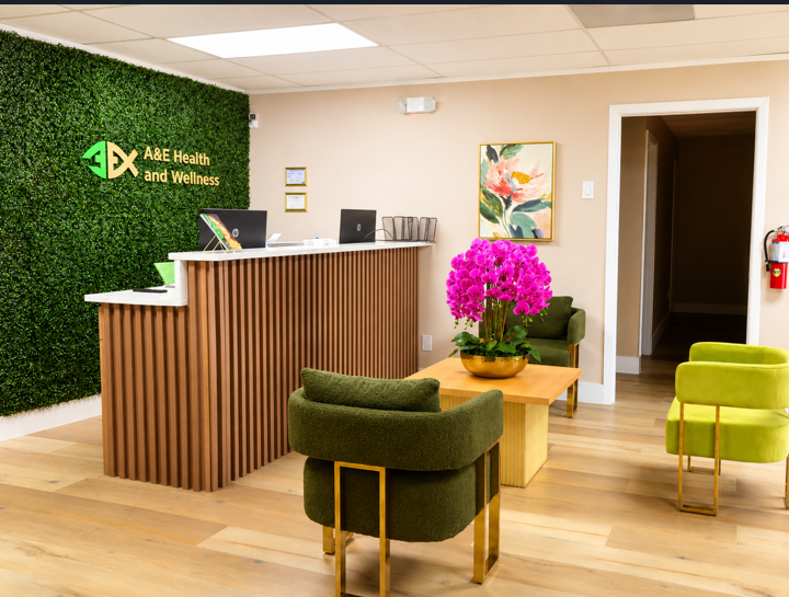 Reception area with green chairs, wooden desk, and pink flowers at A&J Health and Wellness.