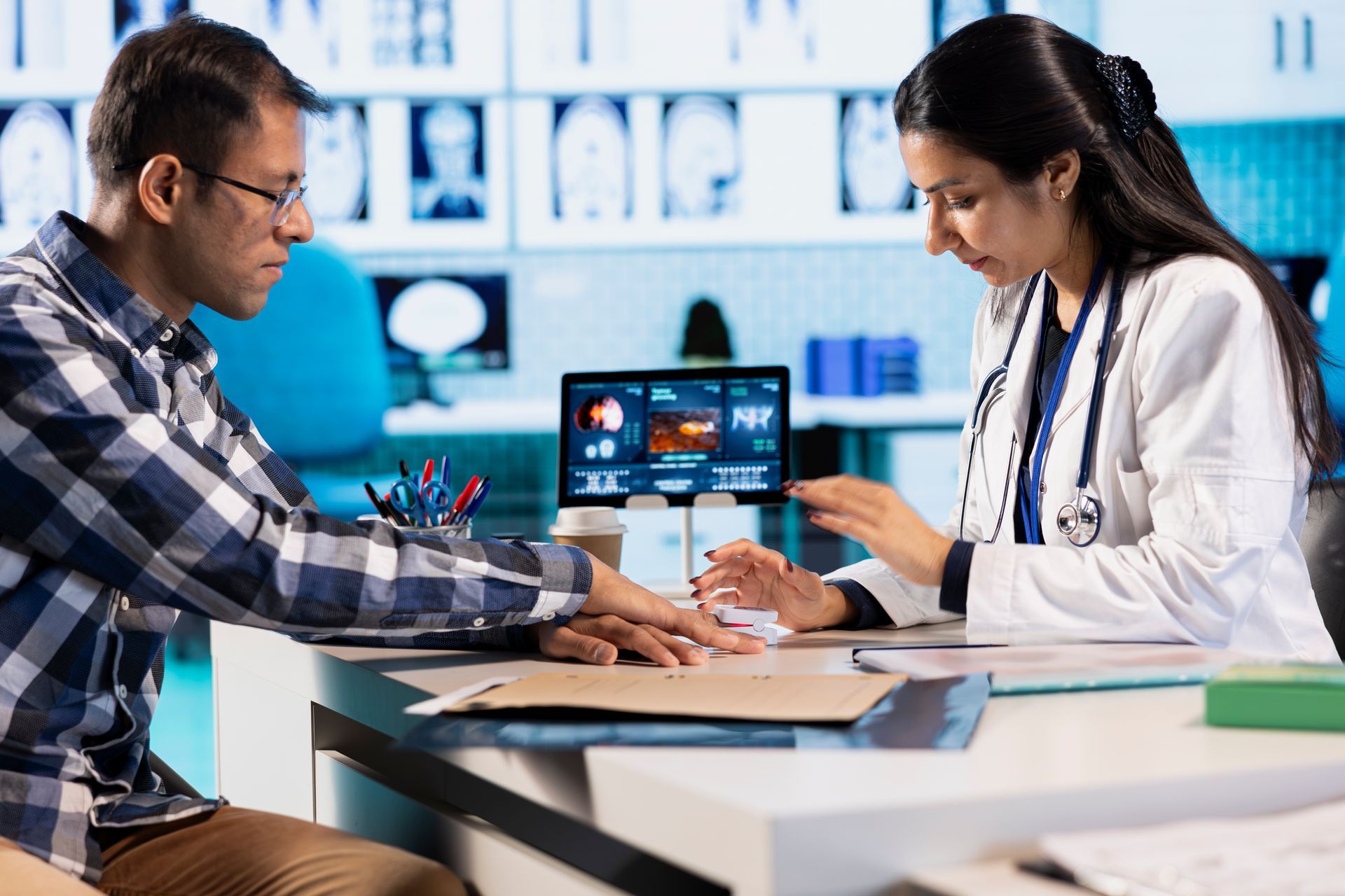 Doctor consulting a patient at a desk in a medical office, showing test results on a laptop.