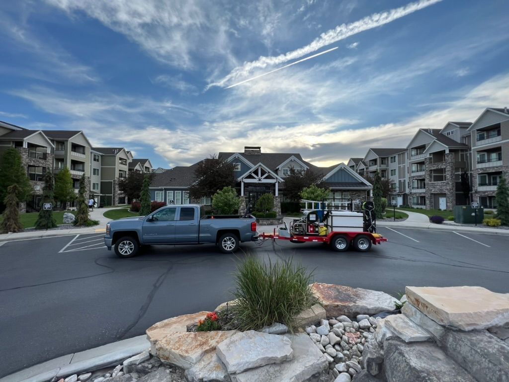 A truck parked in front of a large apartment complex with a sign reading 