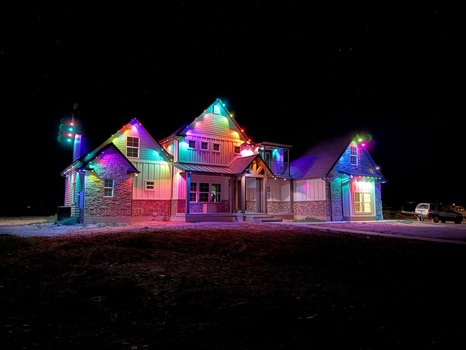 A house beautifully illuminated with colorful Christmas lights at night, creating a festive and joyful atmosphere against a starry sky.