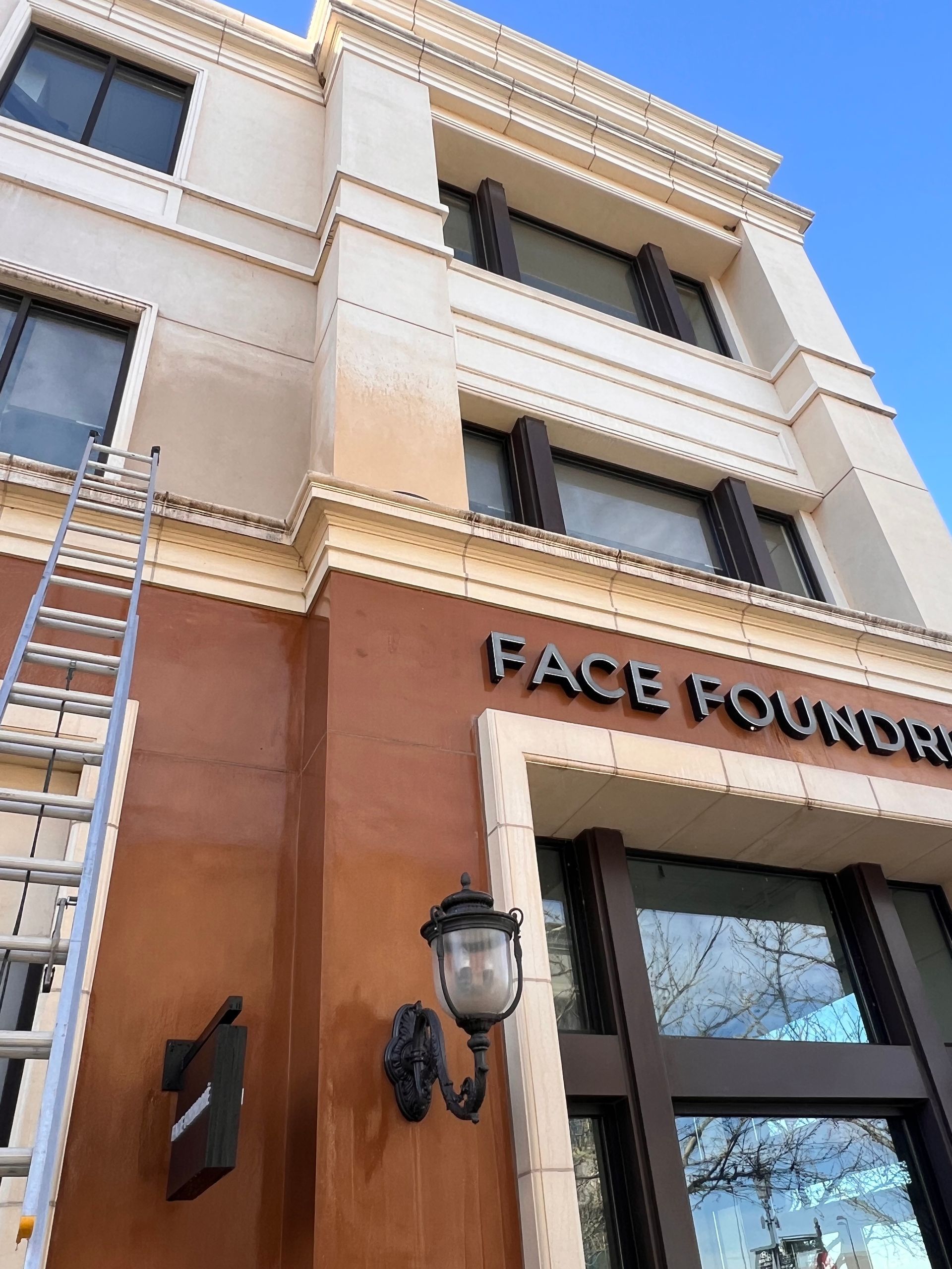The image shows a building facade with large windows and a sign reading 