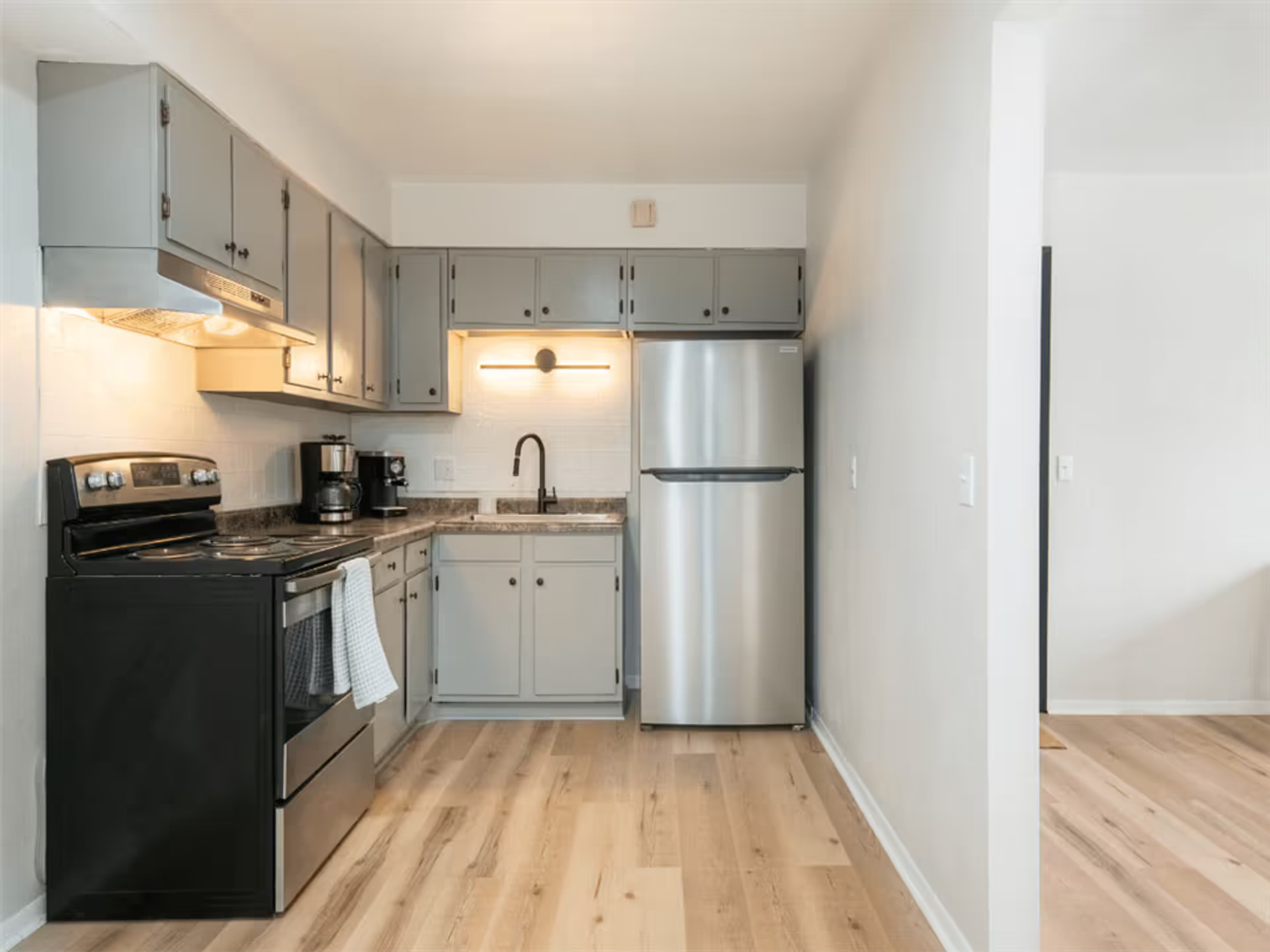 A kitchen with stainless steel appliances and gray cabinets