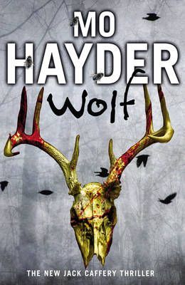 Book cover for “Mo Hayder: Wolf” with a gold stag skull, red antlers, and flying black birds on a gray background