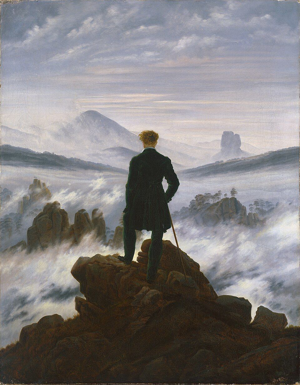Silhouette of a person on a rocky peak overlooking a foggy mountain landscape at dawn