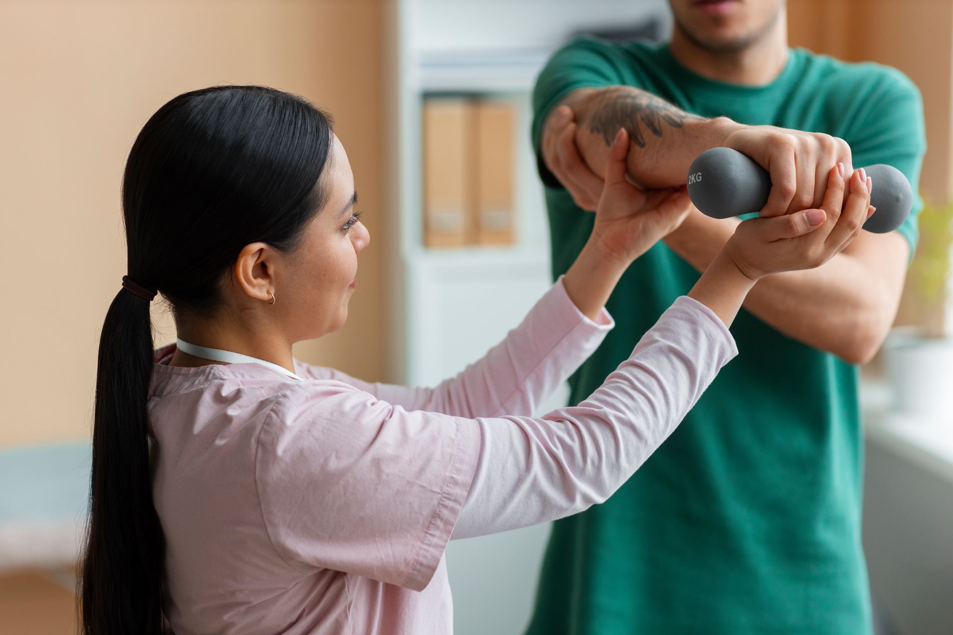 A man is helping a woman lift dumbbells.