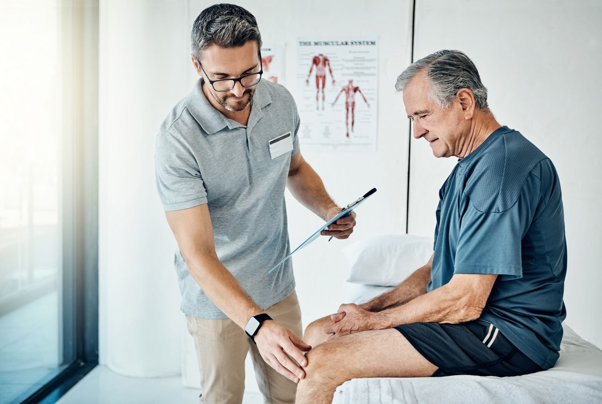 Doctor examining a seated patient’s knee in a bright clinic room