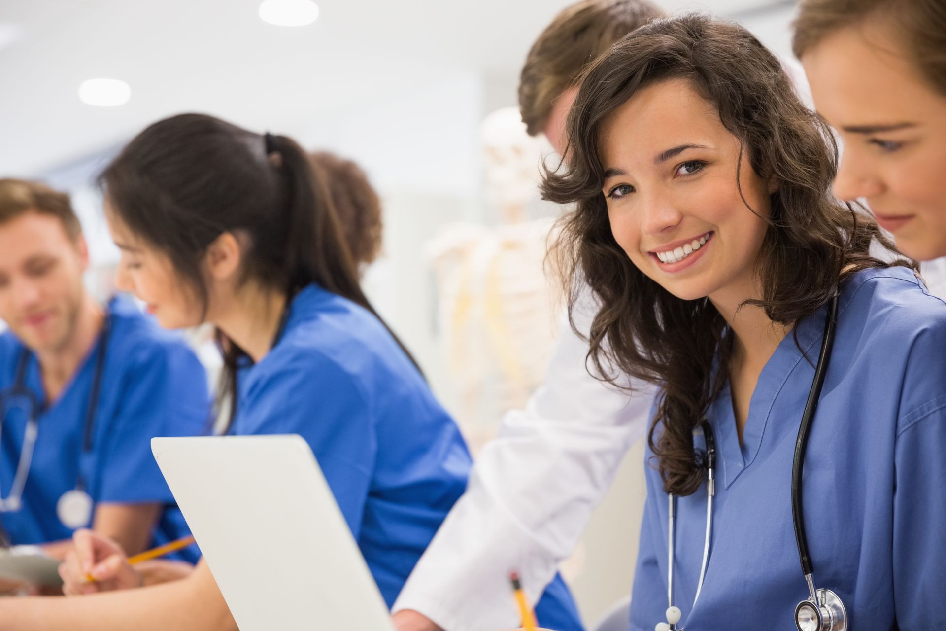 Healthcare trainees working together during a study session with laptops and medical tools visible. Healthcare trainees working together during a study session with laptops and medical tools visible.