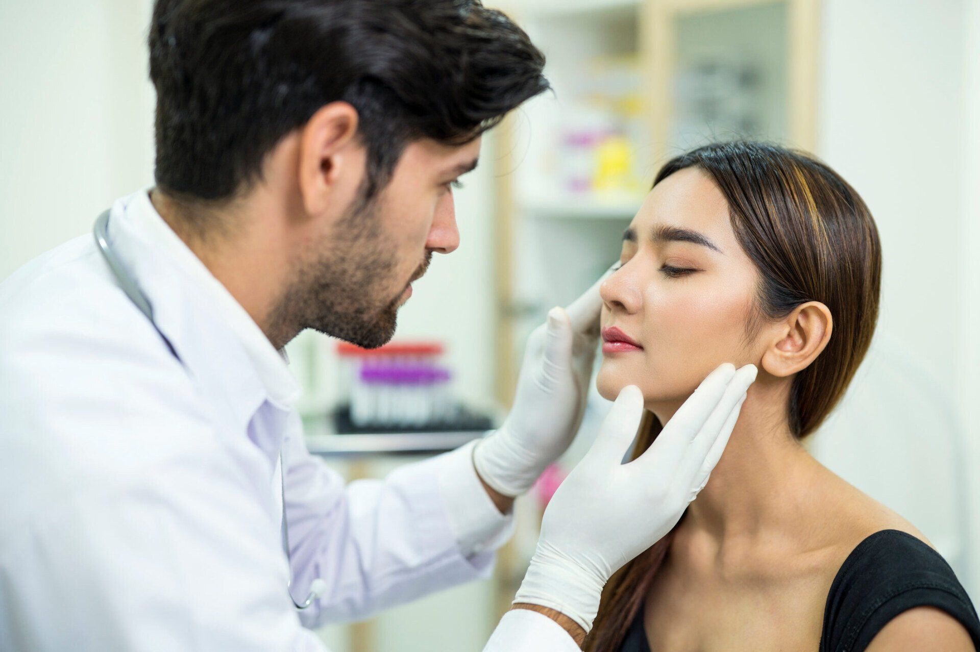 Doctor examining a patient’s face in a clinic, wearing white gloves and a lab coat.
