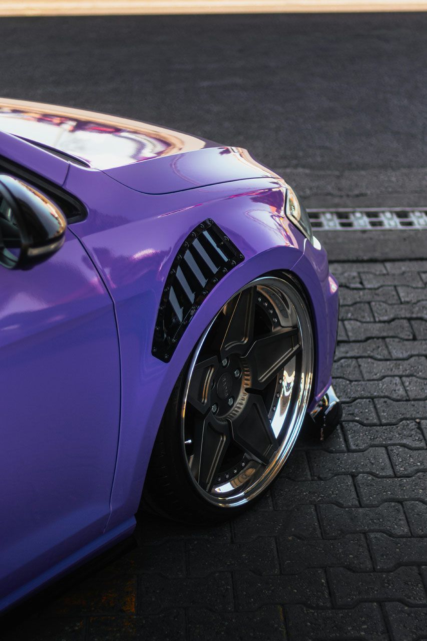 Purple car with custom wheels and a modified fender.