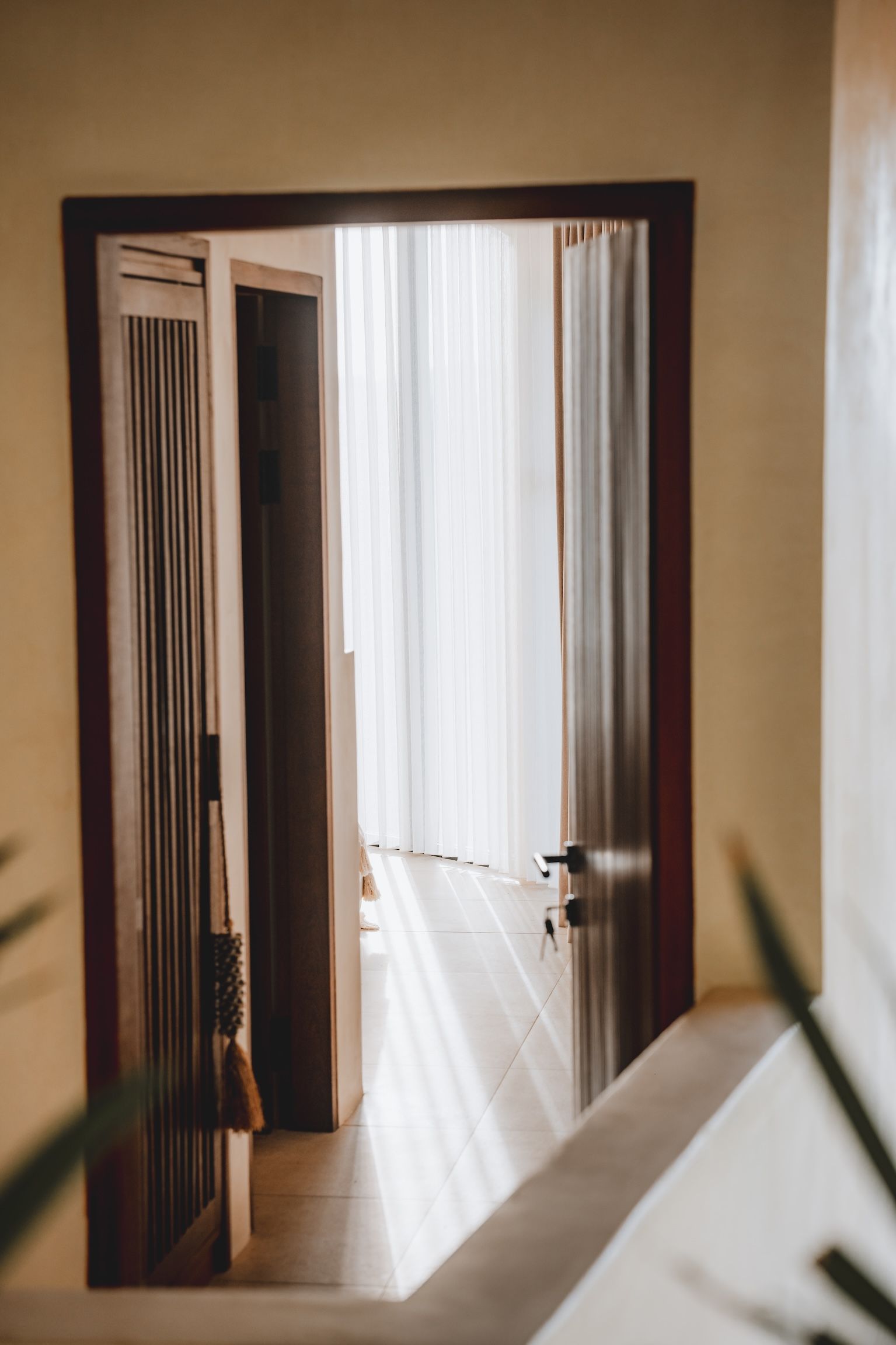Open doorway with sheer curtains letting in soft daylight into a hallway