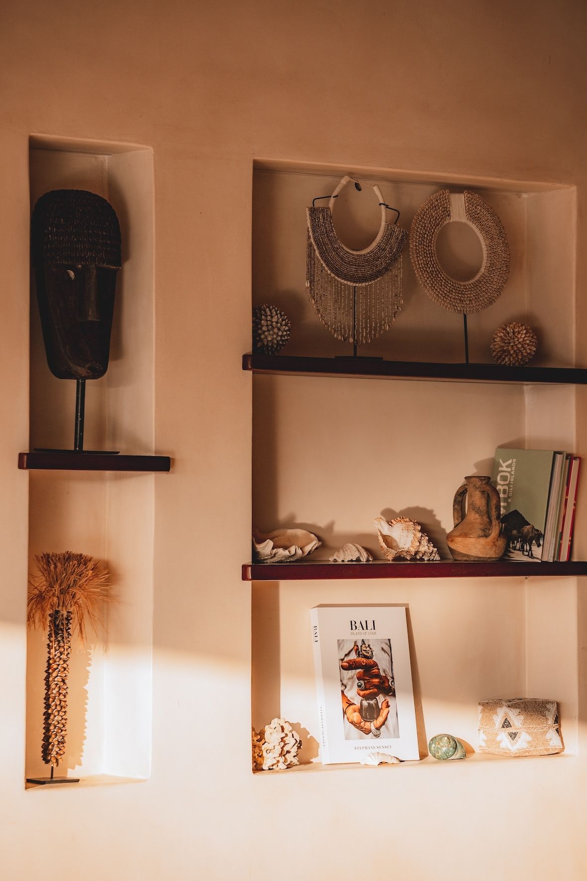 Warm-toned wall shelves displaying jewelry, decor, and framed art in a cozy room.