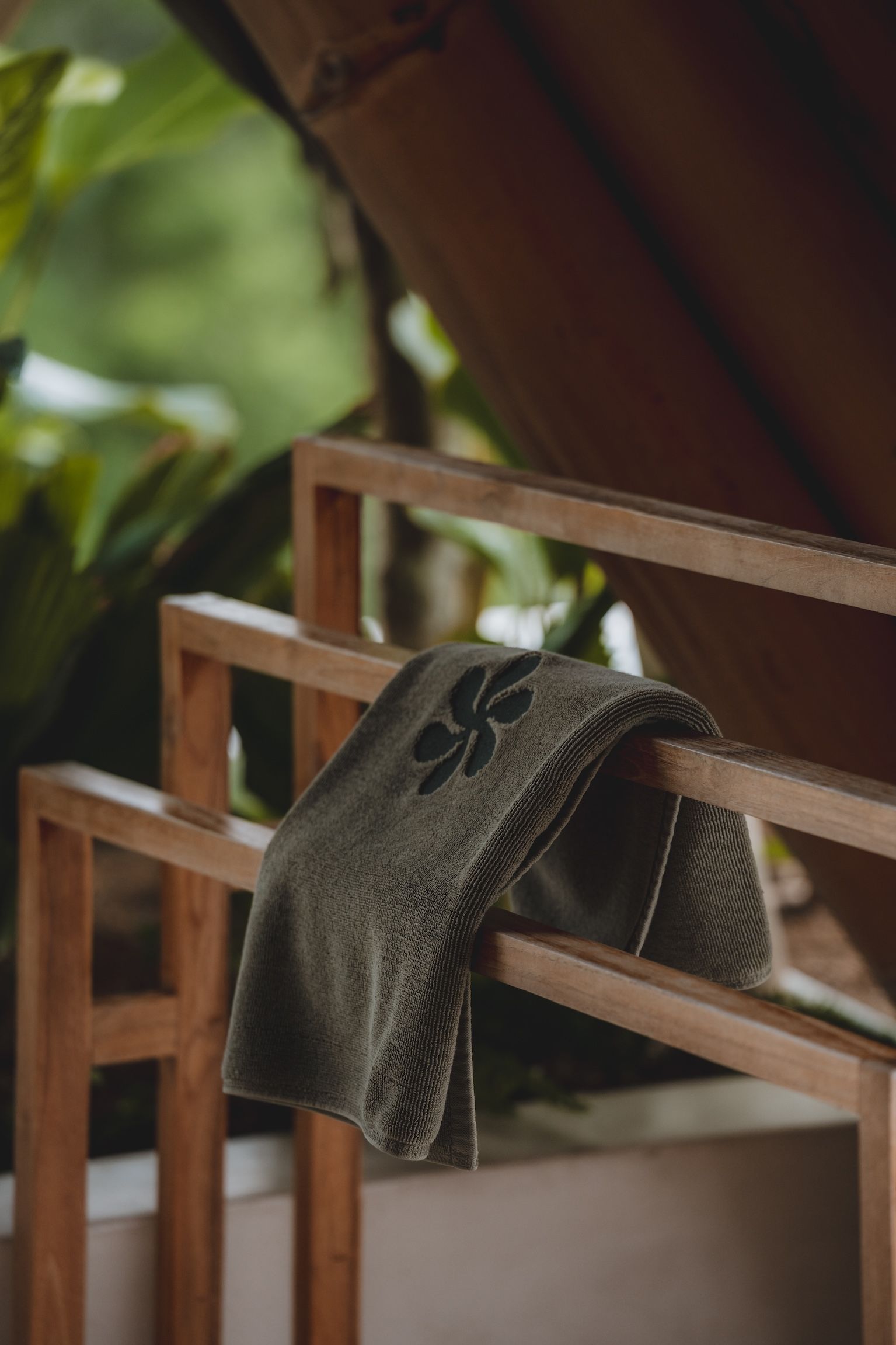 Green patterned towel draped over a wooden chair on a porch