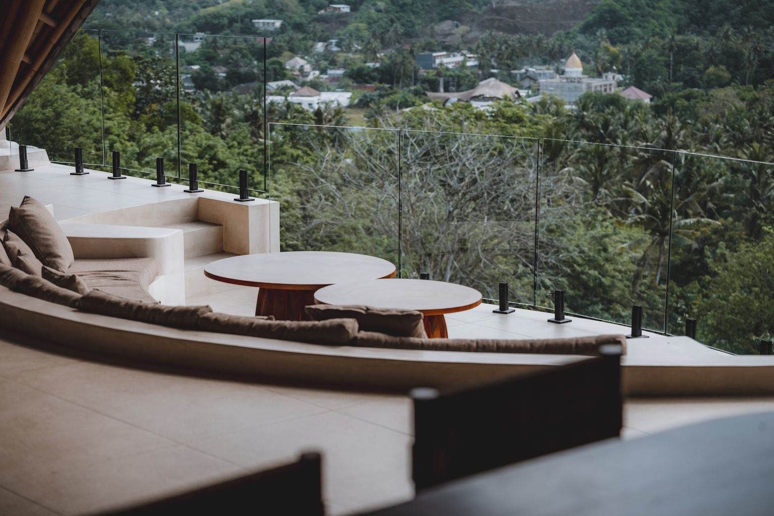 Terrace lounge with curved sofas and tables overlooking a green hillside valley