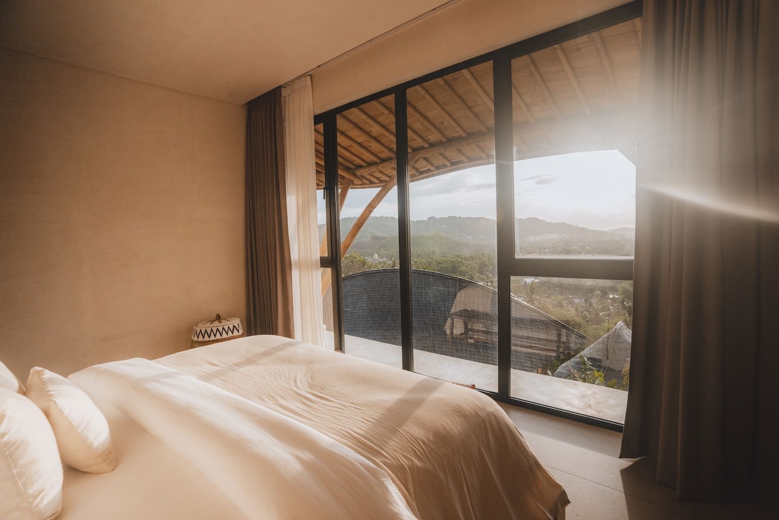 Modern bedroom with bed, sliding glass doors, and sunlit mountain-view balcony