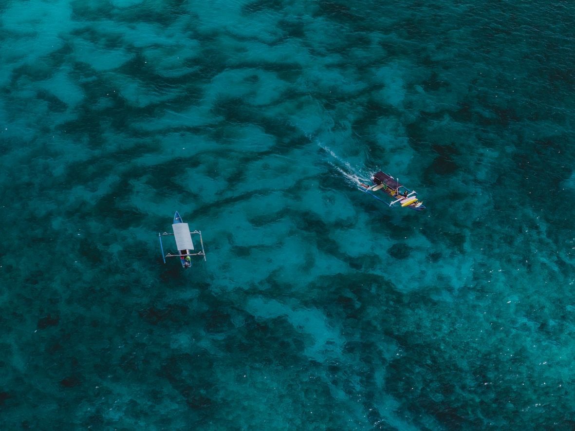 Aerial view of a kayaker on bright turquoise water near a small dock or platform