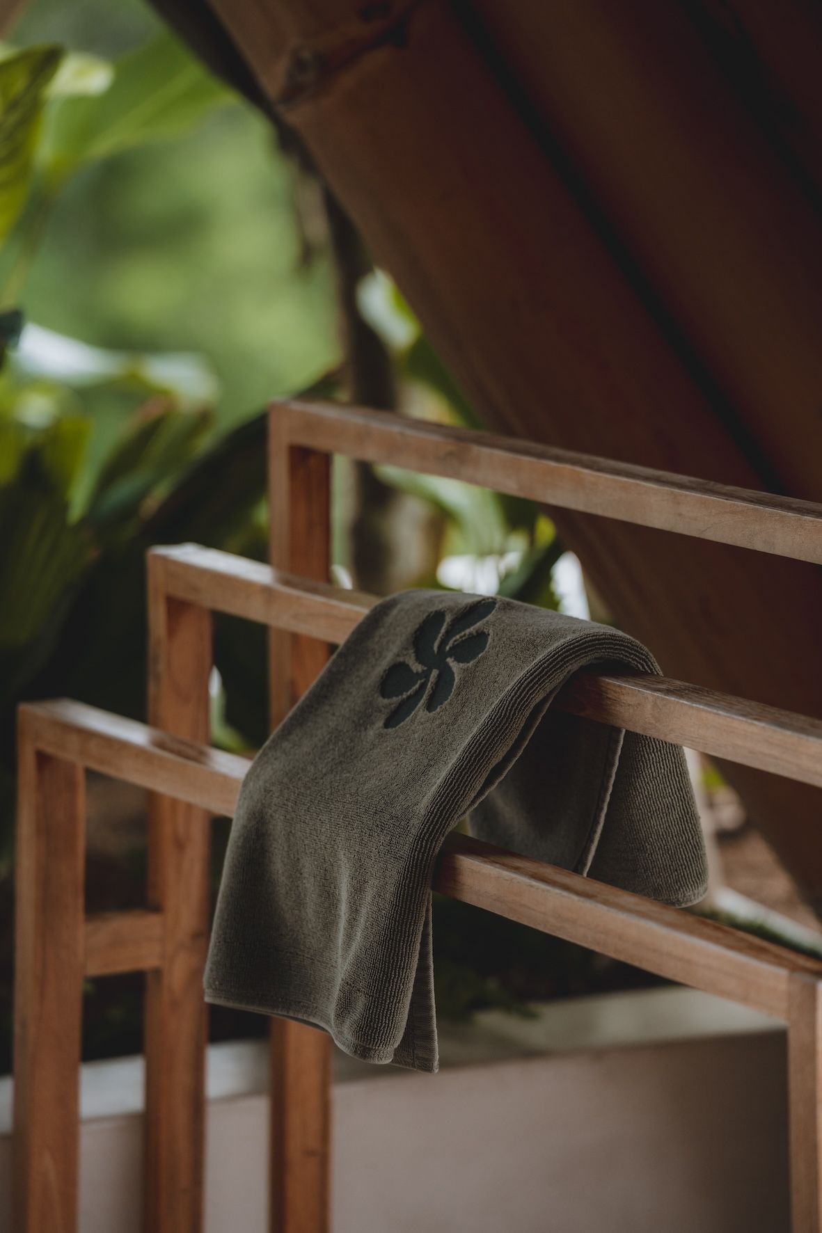 Gray patterned towel draped over a wooden chair on a porch