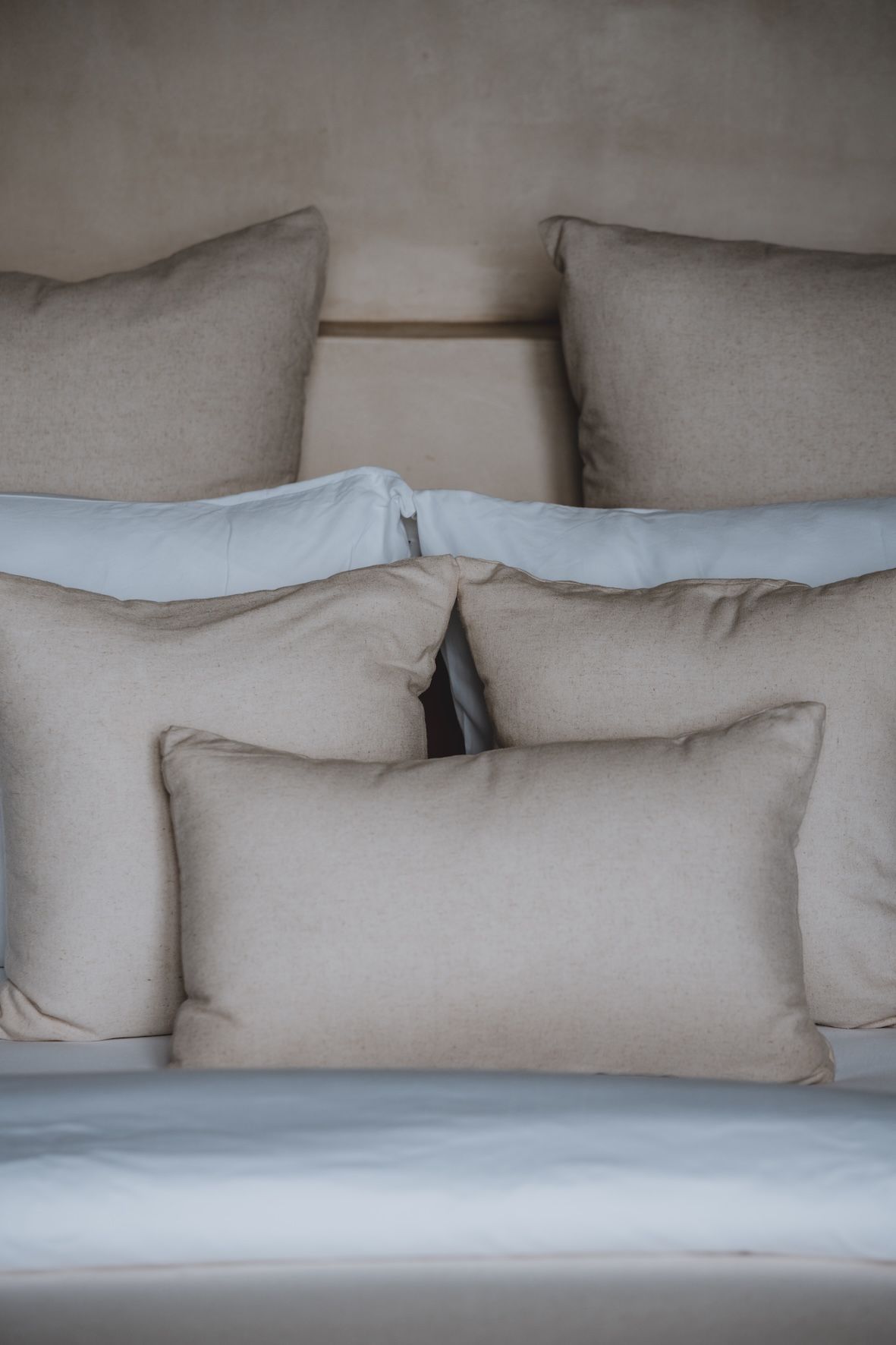 Stacked beige and white pillows on a neatly made bed or sofa