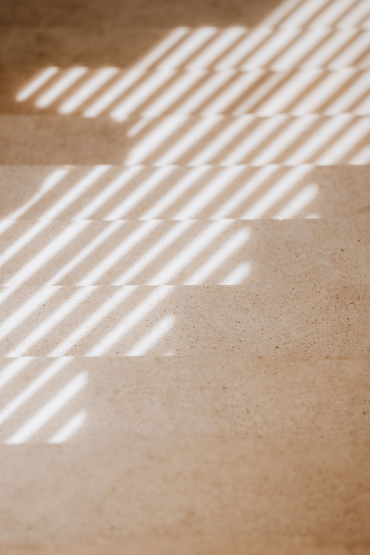 Sunlight casting striped shadows across a beige textured floor
