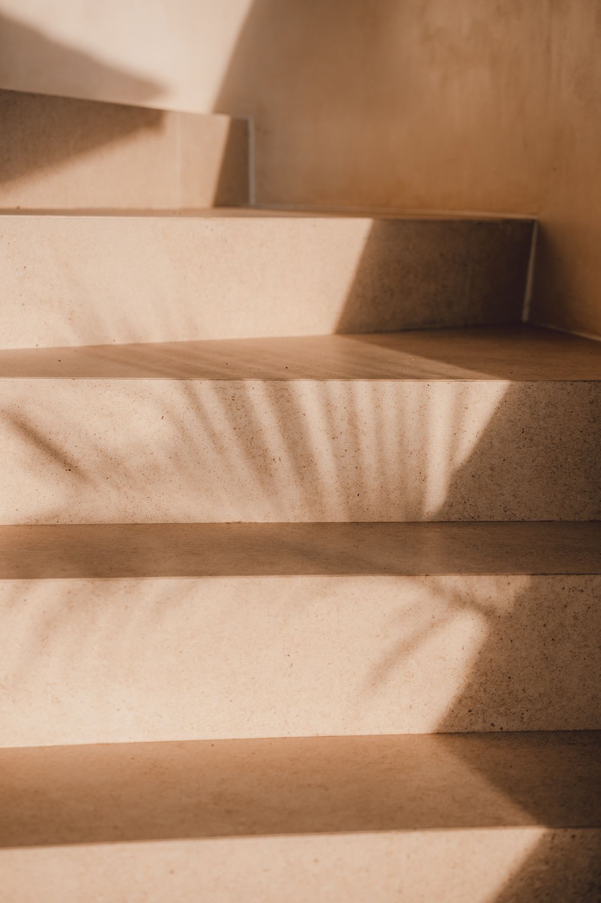 Sunlit beige staircase with strong diagonal shadows on the steps