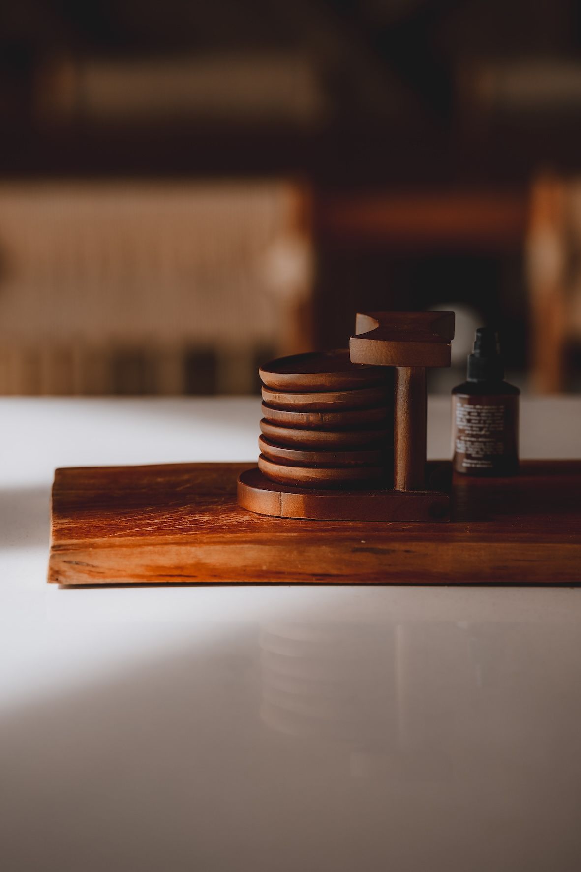 Stacked coins and a small bottle on a wooden table in soft warm light