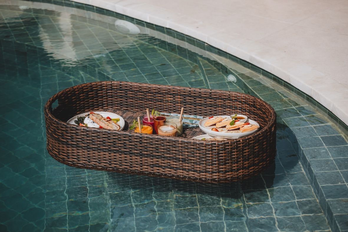 Wicker floating tray with drinks and fruit in a turquoise tiled pool