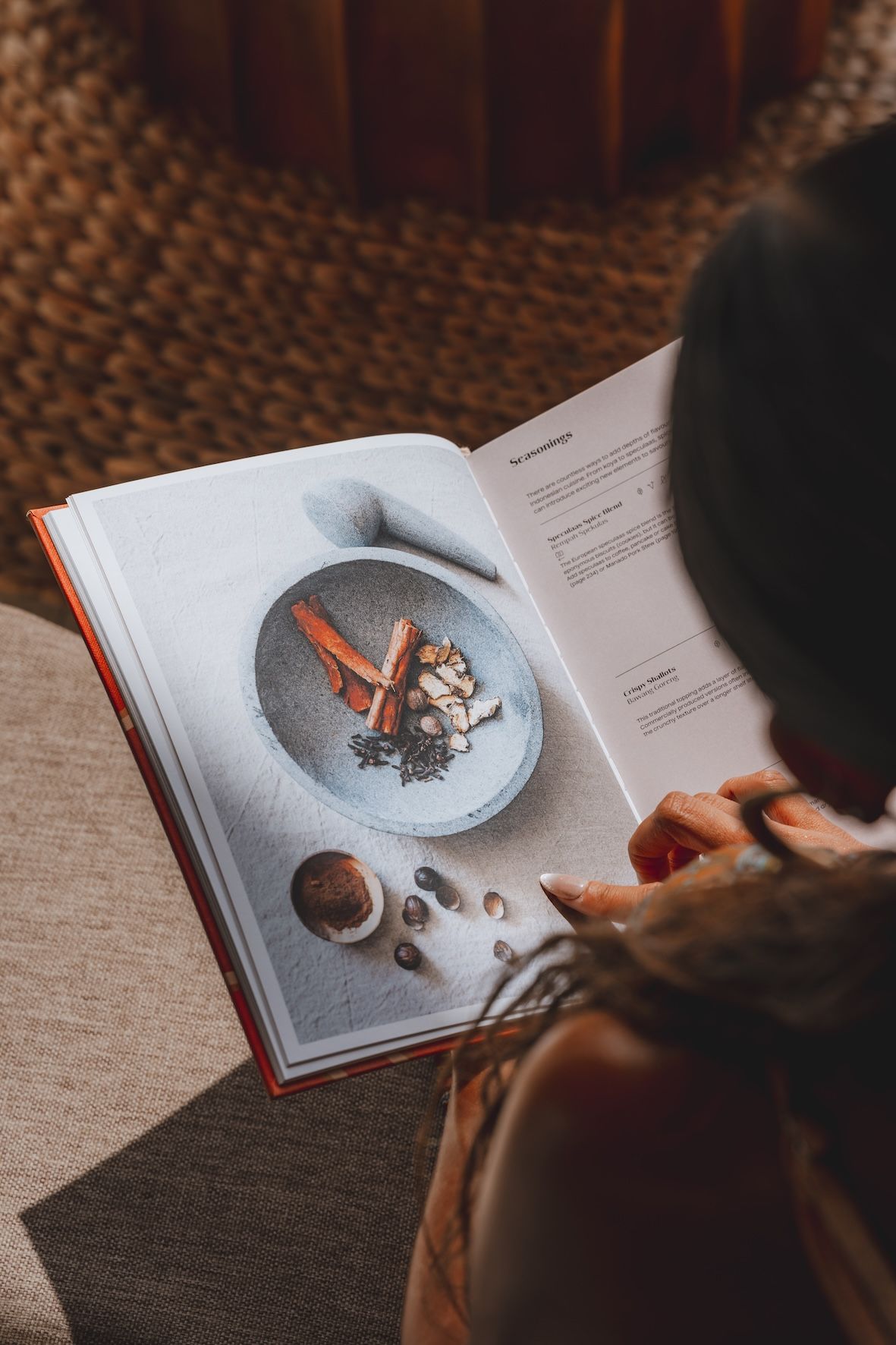 Person reading an open book with photos of food and coffee on a table