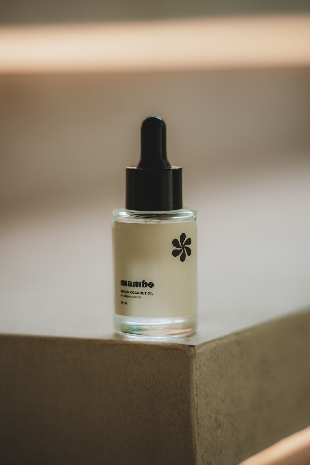 Small dropper bottle with black cap on a cardboard box in soft indoor light