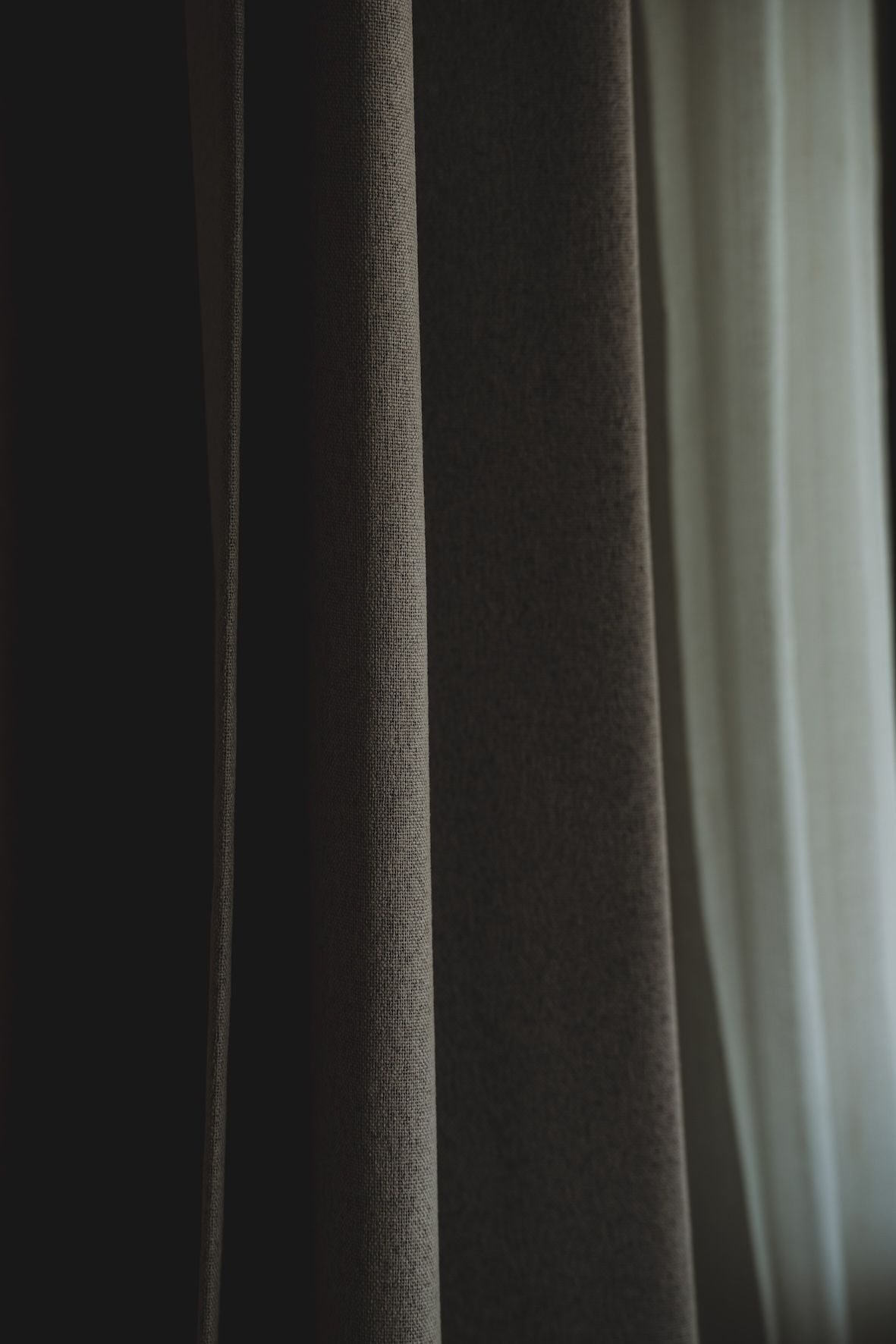Close-up of dark and light curtains with sunlight filtering through the gap