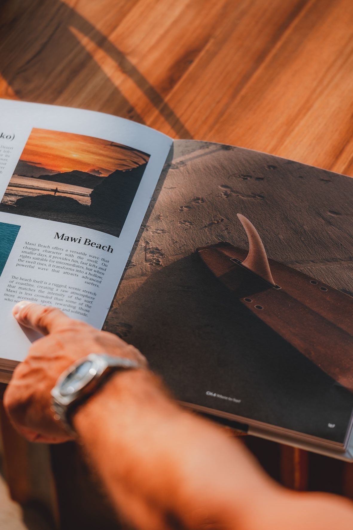 Person flipping through a photo book on a wooden table, with warm sunlight and a wristwatch visible