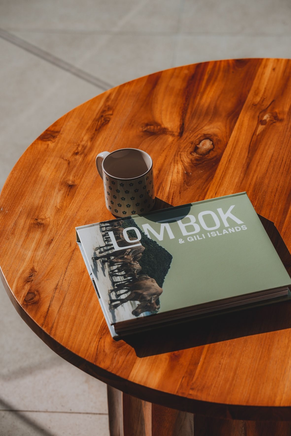 Book and metal cup on a round wooden table