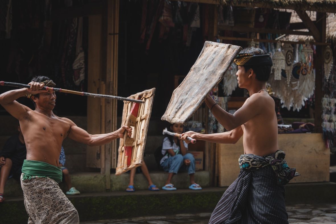 Two people face off with swords in a traditional outdoor combat performance.